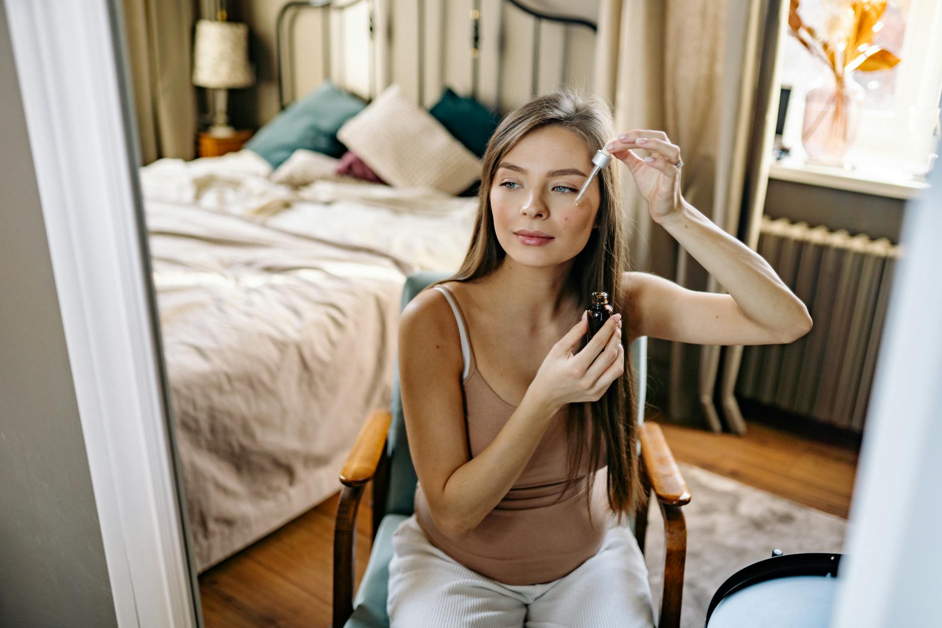 Kobieta w sypialni nakłada krople olejku pipetą