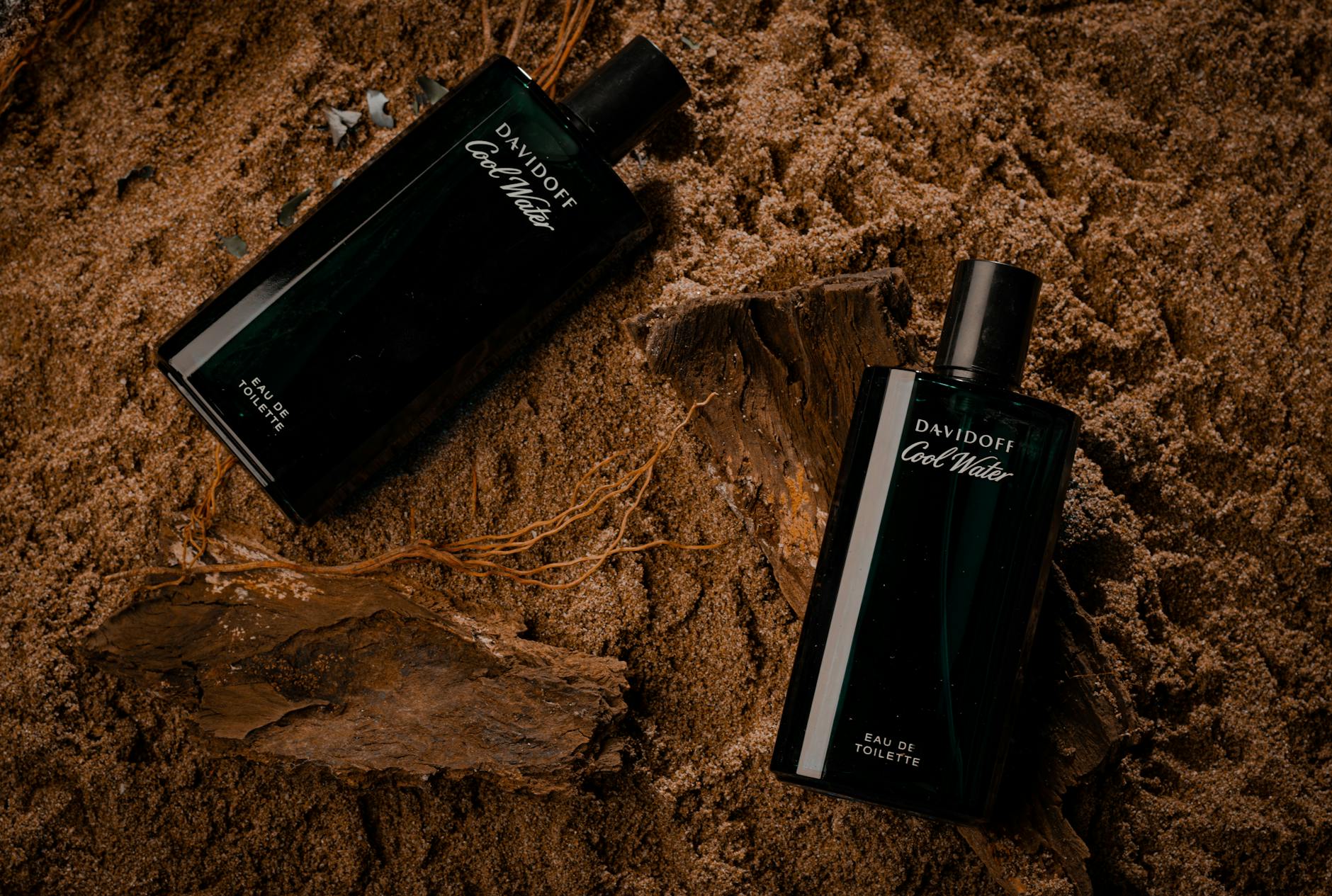 Perfumy w eleganckich flakonach ustawione na piaskowym tle