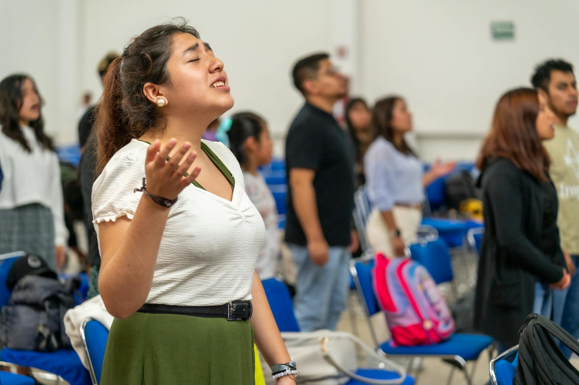 Młodzi dorośli modlący się we wspólnocie, z uniesionymi rękami