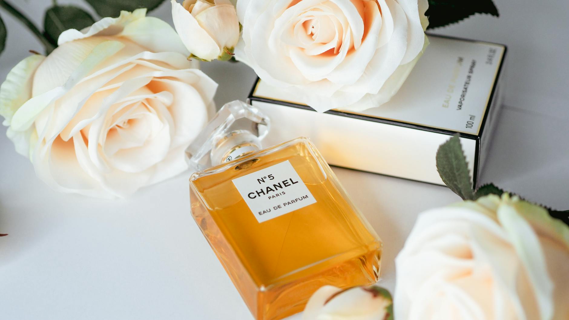 Flakon perfum Chanel No. 5 wśród białych róż