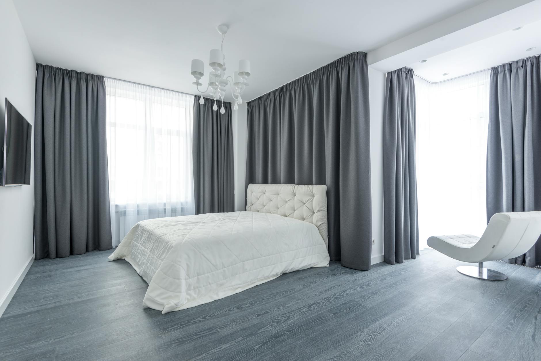 Jasna sypialnia w stylu minimalistycznym z szarymi zasłonami zaciemniającymi