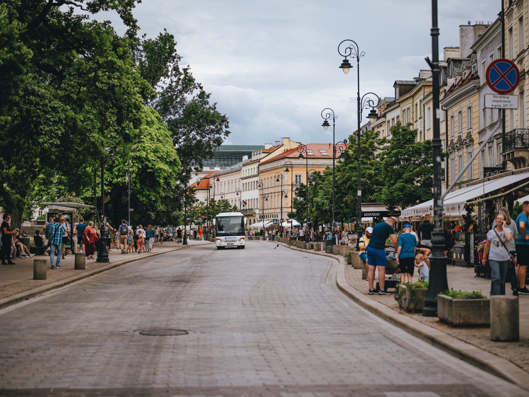 Ruchliwa ulica w centrum Warszawy z kamienicami i przechodniami